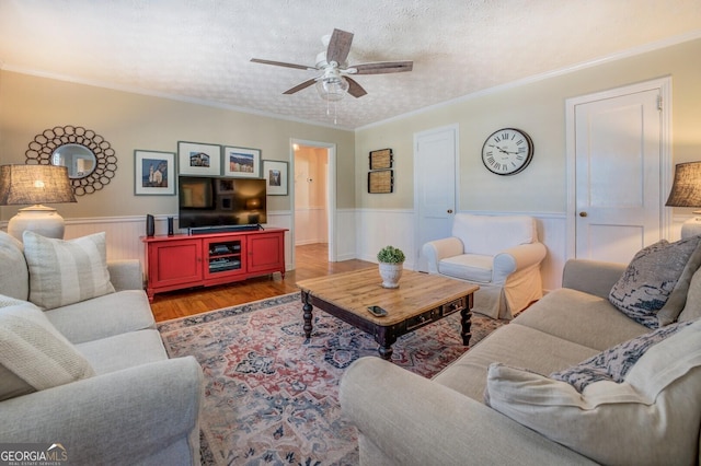 living room featuring wood-type flooring, crown molding, ceiling fan, and a textured ceiling