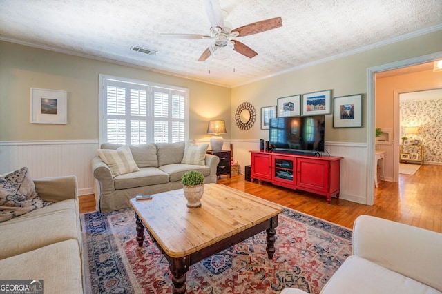 living room with hardwood / wood-style floors, crown molding, a textured ceiling, and ceiling fan