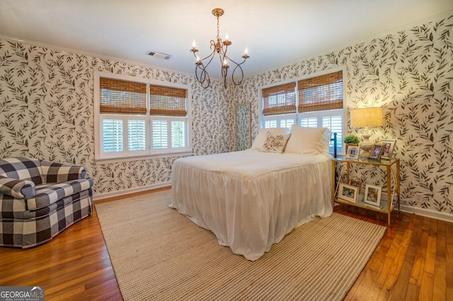 bedroom featuring wood-type flooring, a chandelier, and multiple windows