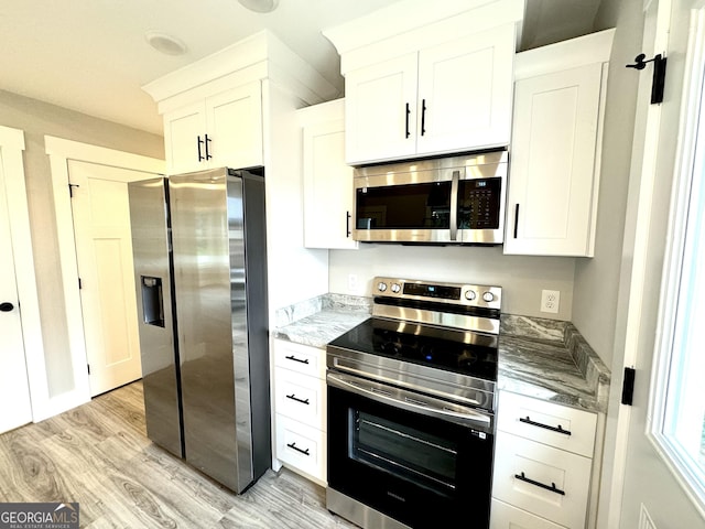 kitchen with stainless steel appliances, light stone countertops, white cabinets, and light hardwood / wood-style flooring