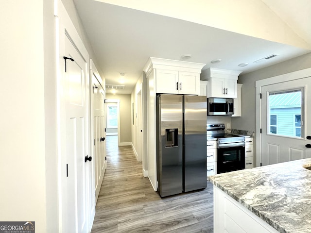 kitchen with white cabinetry, stainless steel appliances, light stone countertops, and light hardwood / wood-style floors