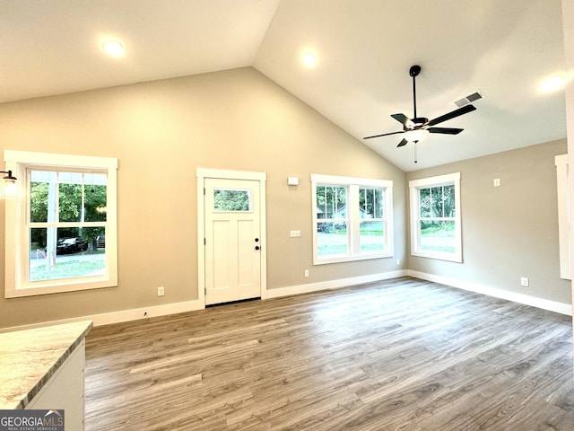 unfurnished living room with hardwood / wood-style flooring, a healthy amount of sunlight, and high vaulted ceiling