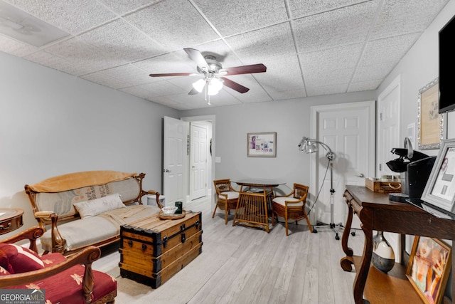 living room featuring a drop ceiling, light hardwood / wood-style flooring, and ceiling fan