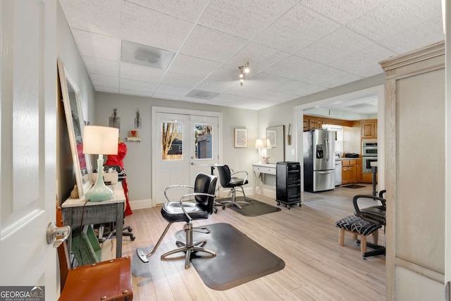 workout room with a paneled ceiling and light wood-type flooring