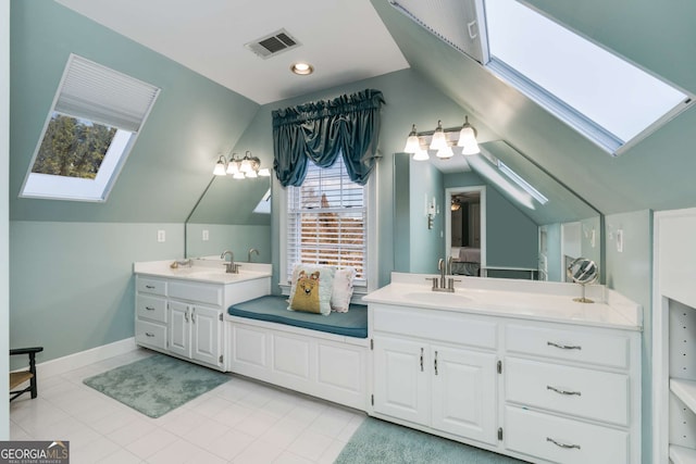 bathroom with vanity, tile patterned flooring, and vaulted ceiling with skylight