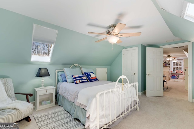 carpeted bedroom featuring lofted ceiling with skylight, a closet, and ceiling fan