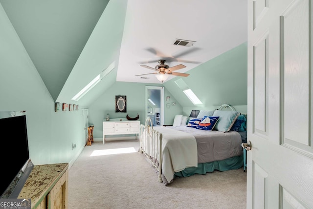 bedroom featuring ceiling fan, vaulted ceiling with skylight, and light carpet