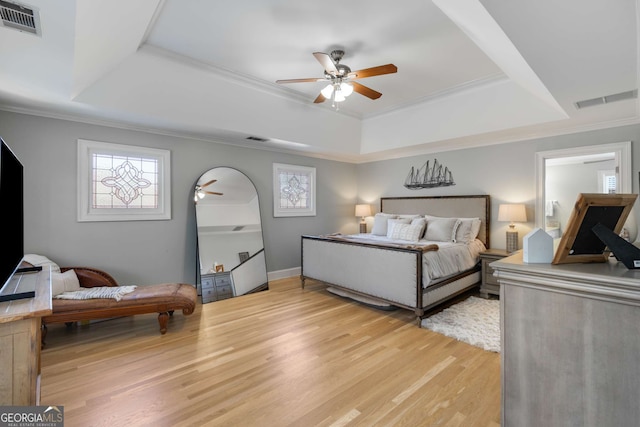 bedroom with crown molding, ceiling fan, a raised ceiling, and light hardwood / wood-style flooring