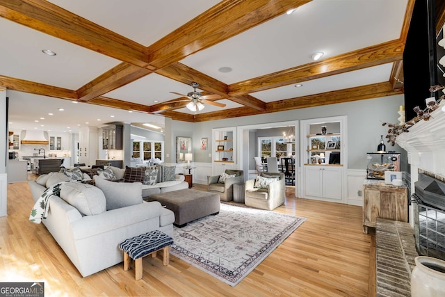 living room featuring beamed ceiling, coffered ceiling, sink, and light wood-type flooring