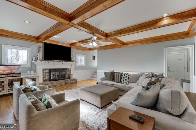 living room with beamed ceiling, coffered ceiling, a fireplace, and hardwood / wood-style flooring