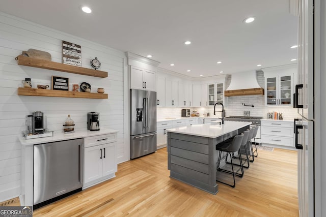 kitchen featuring high quality appliances, custom range hood, white cabinets, and a kitchen breakfast bar