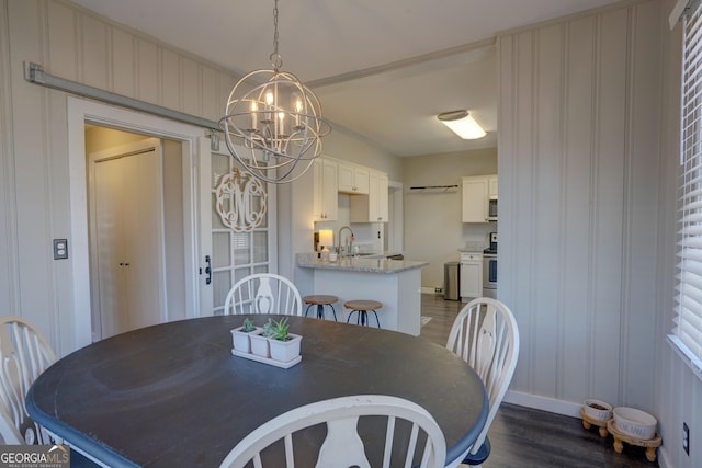 dining space with a notable chandelier, dark wood-type flooring, and sink