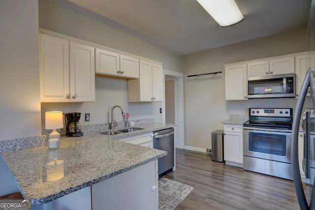 kitchen with sink, white cabinetry, stainless steel appliances, light stone counters, and kitchen peninsula