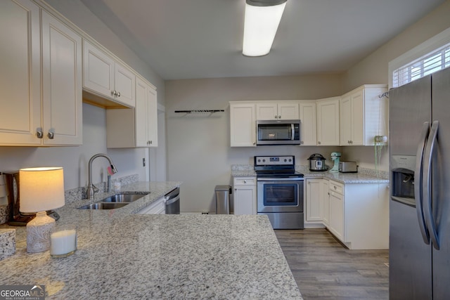 kitchen featuring appliances with stainless steel finishes, sink, white cabinets, and light stone counters