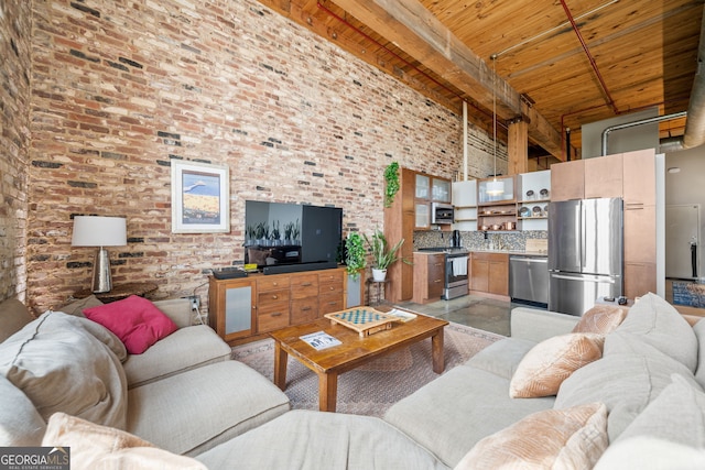 living room with beam ceiling, a towering ceiling, wooden ceiling, and brick wall