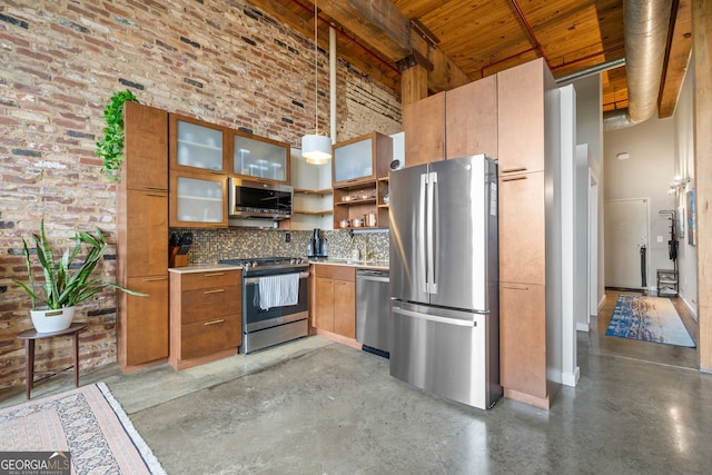 kitchen with hanging light fixtures, appliances with stainless steel finishes, a towering ceiling, brick wall, and backsplash