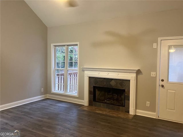 unfurnished living room with dark hardwood / wood-style floors, a tiled fireplace, and vaulted ceiling