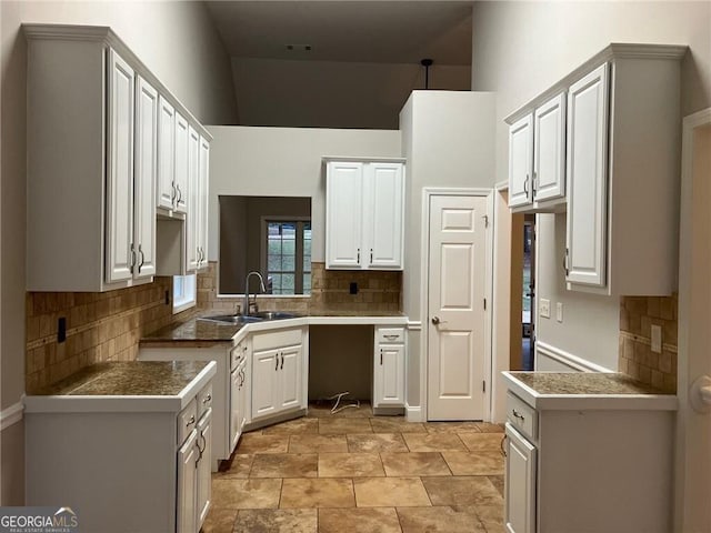 kitchen featuring tasteful backsplash, sink, and white cabinets