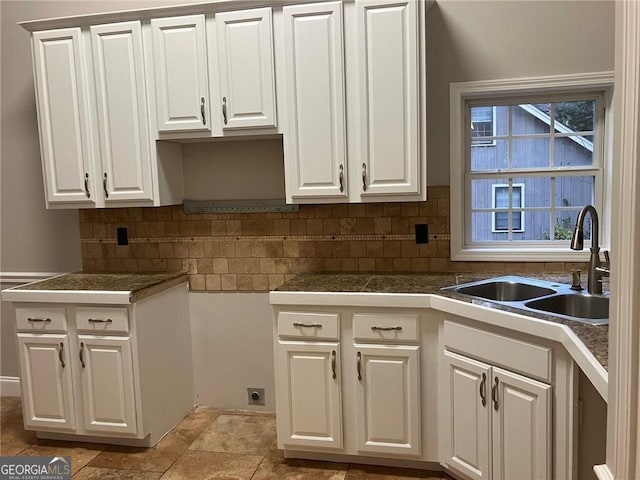 kitchen featuring sink, white cabinets, and backsplash