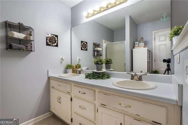 bathroom featuring vanity, a shower with door, and a textured ceiling