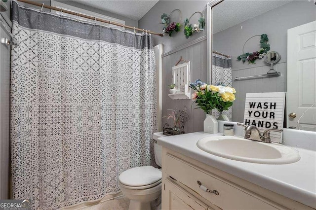 bathroom featuring vanity, a textured ceiling, and toilet