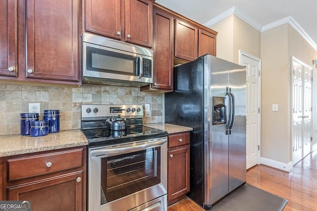 kitchen featuring light stone counters, crown molding, stainless steel appliances, backsplash, and light wood-style flooring