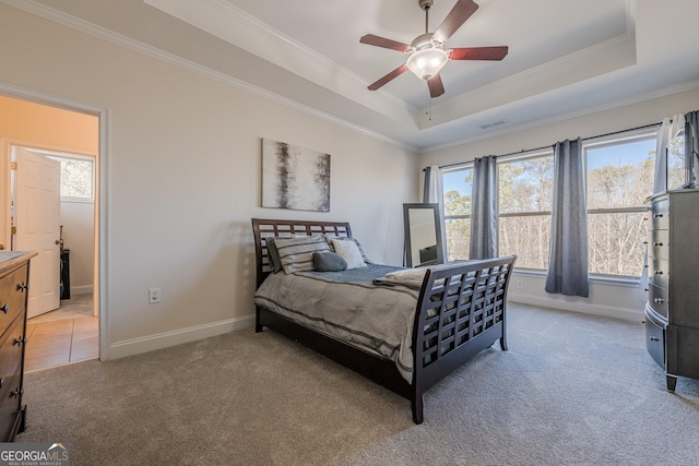 bedroom with ornamental molding, a tray ceiling, and light colored carpet