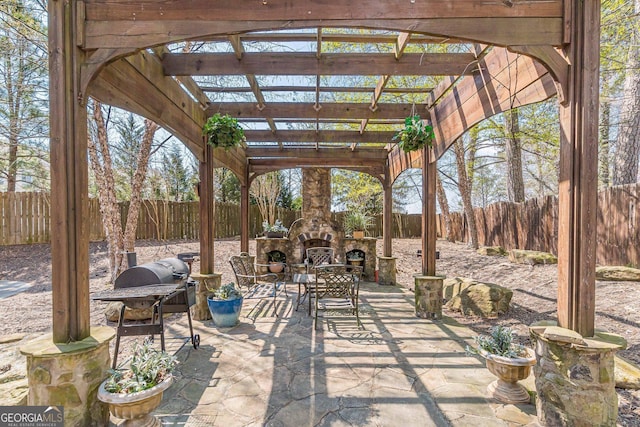 view of patio with outdoor dining space, an outdoor stone fireplace, a fenced backyard, and a pergola