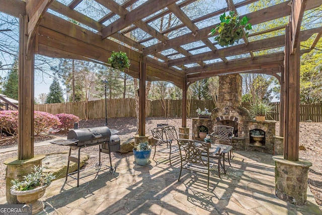 view of patio featuring a fenced backyard, an outdoor stone fireplace, a pergola, and area for grilling