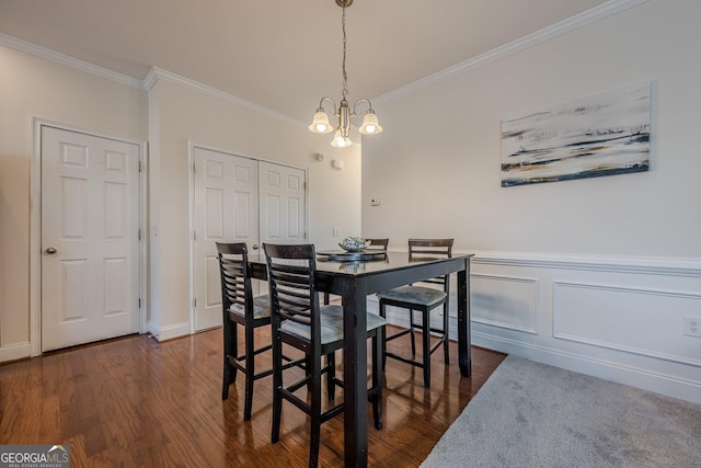 dining space with dark wood-style floors, wainscoting, ornamental molding, and an inviting chandelier