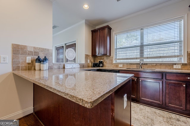 kitchen featuring light stone counters, a peninsula, a sink, ornamental molding, and decorative backsplash