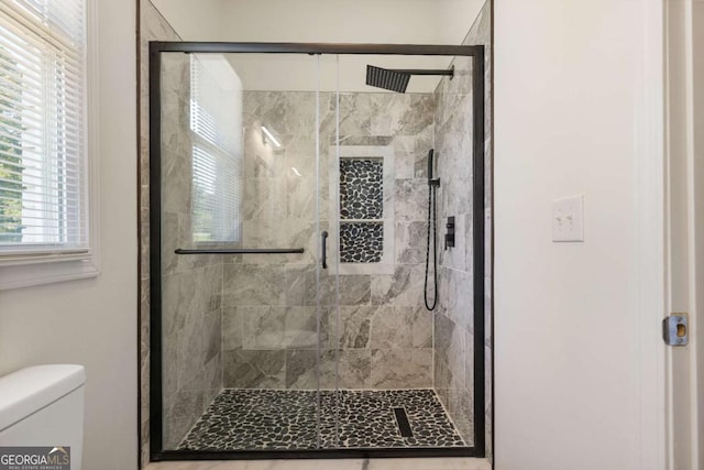 bathroom featuring toilet and a shower with shower door