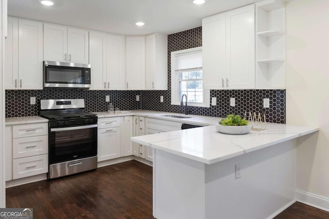 kitchen with white cabinetry, appliances with stainless steel finishes, kitchen peninsula, and sink