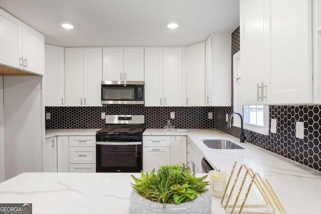 kitchen with white cabinetry, appliances with stainless steel finishes, light stone countertops, and sink