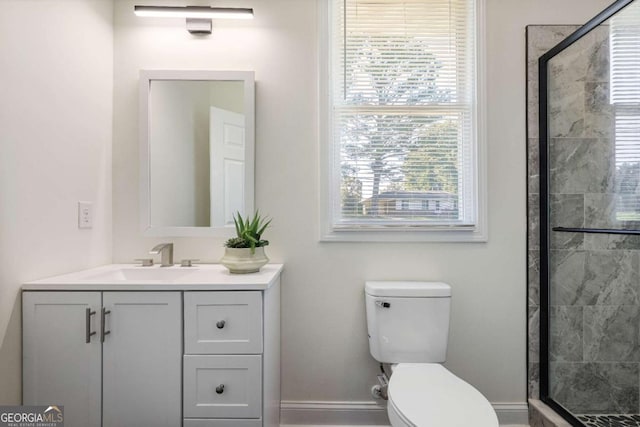 bathroom featuring vanity, a shower with door, and toilet