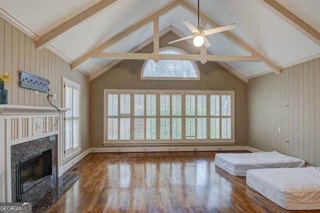 interior space with beam ceiling, hardwood / wood-style flooring, plenty of natural light, and a high end fireplace