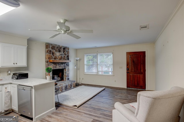 living room with a fireplace, ornamental molding, light hardwood / wood-style floors, and ceiling fan