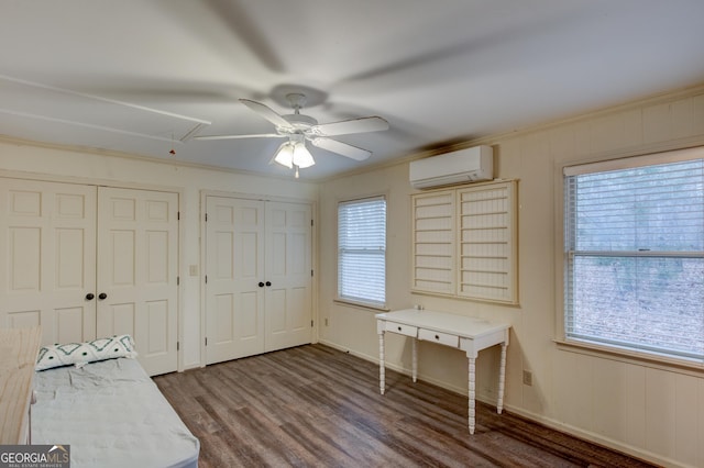 bedroom featuring dark wood-type flooring, an AC wall unit, multiple closets, ornamental molding, and ceiling fan