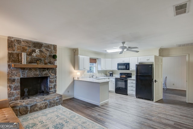 kitchen with white cabinetry, wood-type flooring, kitchen peninsula, and black appliances