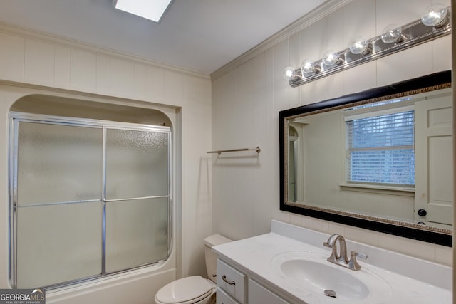 full bathroom featuring crown molding, toilet, vanity, and bath / shower combo with glass door