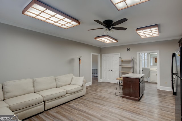 living room featuring ornamental molding, ceiling fan, and light wood-type flooring