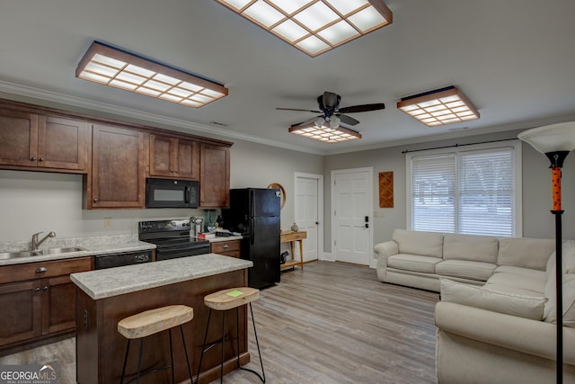 kitchen with a breakfast bar, sink, a center island, ornamental molding, and black appliances