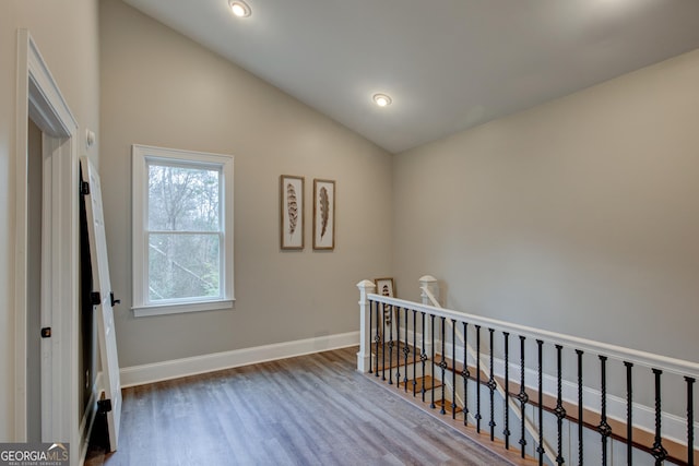 hallway with lofted ceiling and hardwood / wood-style floors