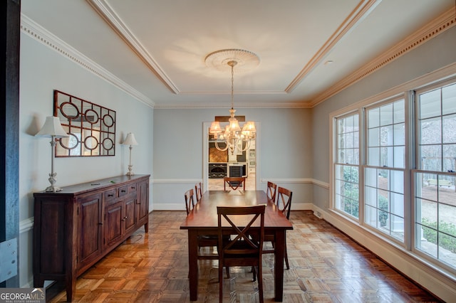 dining room featuring crown molding, parquet flooring, and a notable chandelier