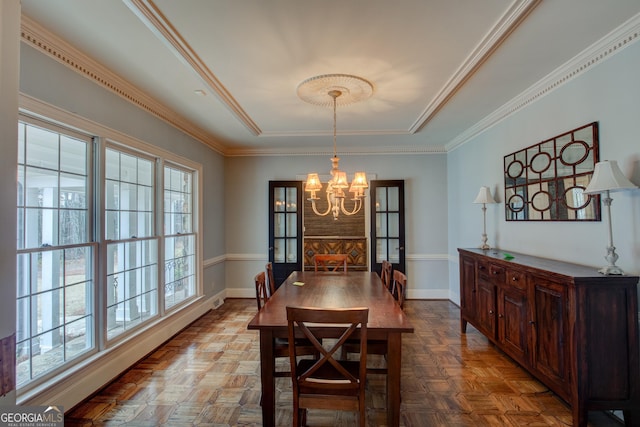 dining room with parquet flooring, ornamental molding, and a notable chandelier