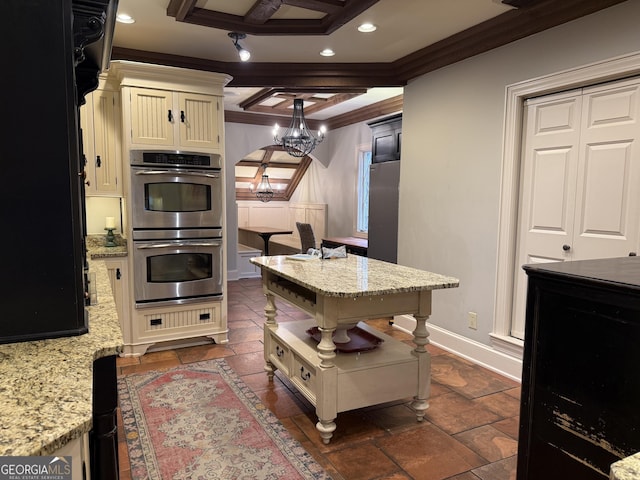 kitchen featuring pendant lighting, ornamental molding, light stone countertops, and stainless steel double oven