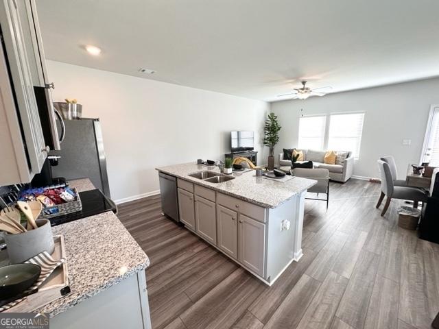 kitchen featuring sink, dark wood-type flooring, an island with sink, and appliances with stainless steel finishes