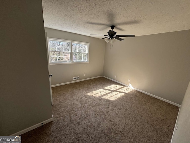 spare room featuring baseboards, visible vents, a ceiling fan, a textured ceiling, and dark carpet