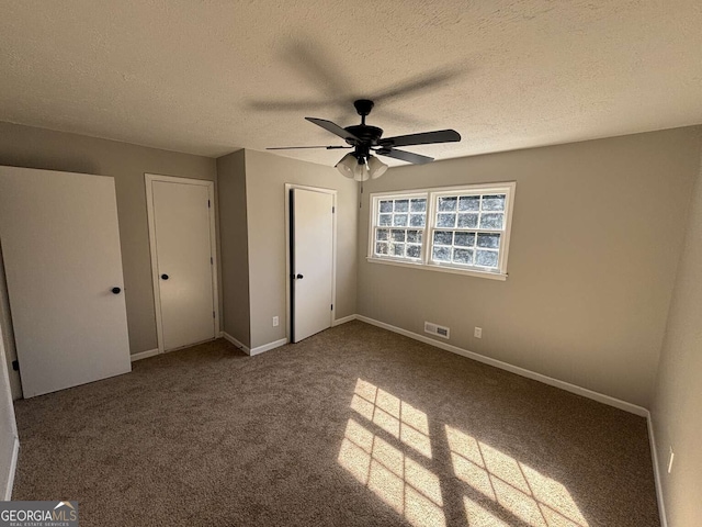 unfurnished bedroom with a textured ceiling, carpet flooring, a ceiling fan, visible vents, and baseboards