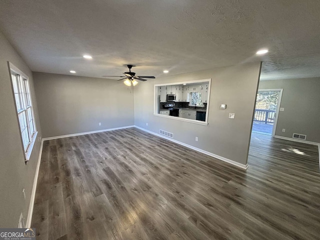 unfurnished living room featuring visible vents, baseboards, and wood finished floors